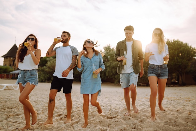 Grupo de amigos anima y bebe cervezas en la playa Joven amigo relajándose y haciendo un picnic Suummertime