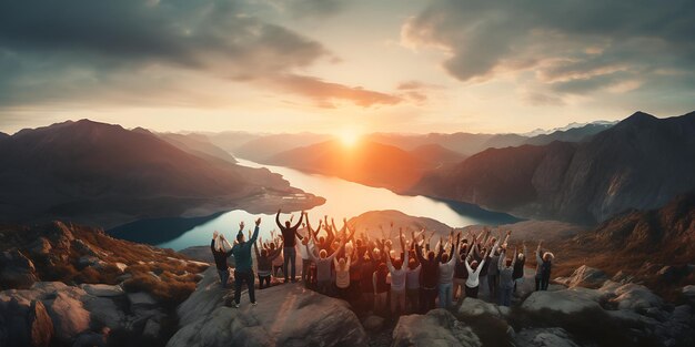 Grupo de amigos aplaudiendo con las manos levantadas en la cima de la montaña durante la puesta de sol