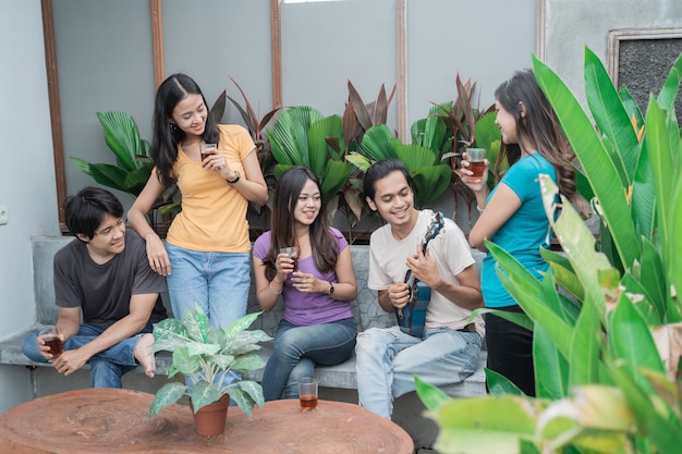 Grupo de amigos asiáticos divirtiéndose cantando y tocando la guitarra juntos en el patio trasero