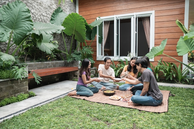 Grupo de amigos asiáticos divirtiéndose mientras come y bebe en el patio trasero