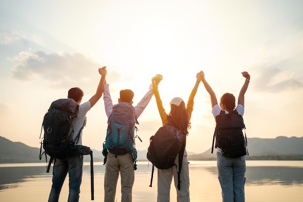 Un grupo de amigos asiáticos mochileros y caminando para hacer un picnic y acampar y Levanta tu mano alegre emoción