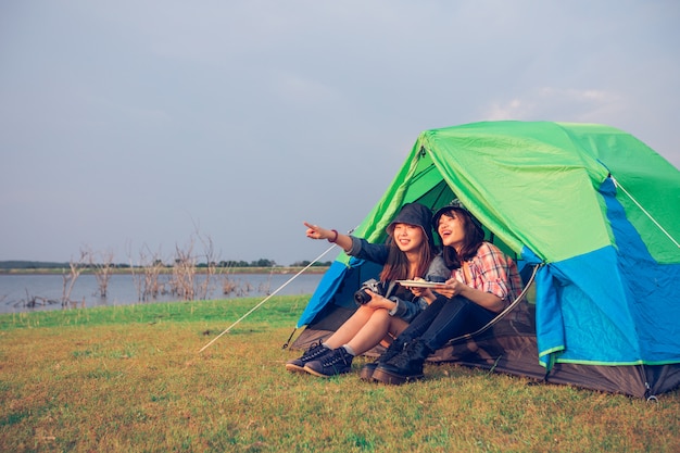 Un grupo de amigos asiáticos turistas bebiendo juntos con felicidad en verano mientras acampan