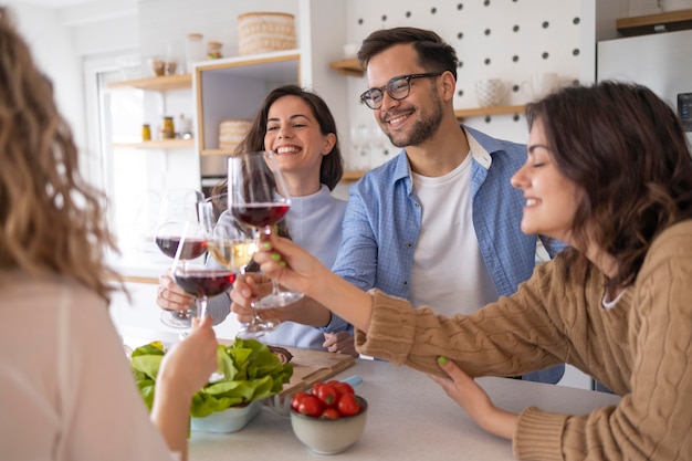 Foto grupo de amigos bebiendo vino en la cocina