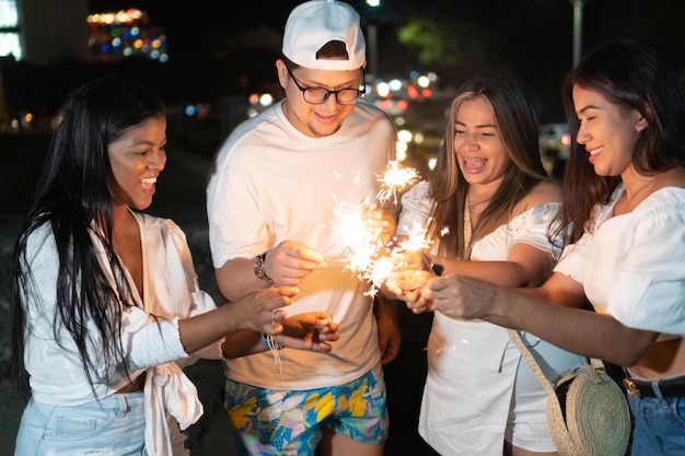 Grupo de amigos con bengalas durante la fiesta al aire libre