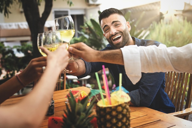 Grupo de amigos con un brindis de celebración con vino blanco en la tarde gente divirtiéndose juntos