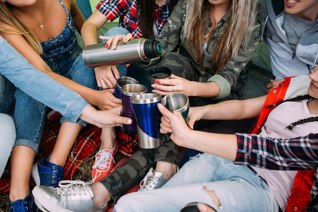 El grupo de amigos se calienta con té en la carpa. Tiempo de picnic.