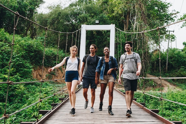 Grupo de amigos caminando sobre el puente en una aventura de campo tropical