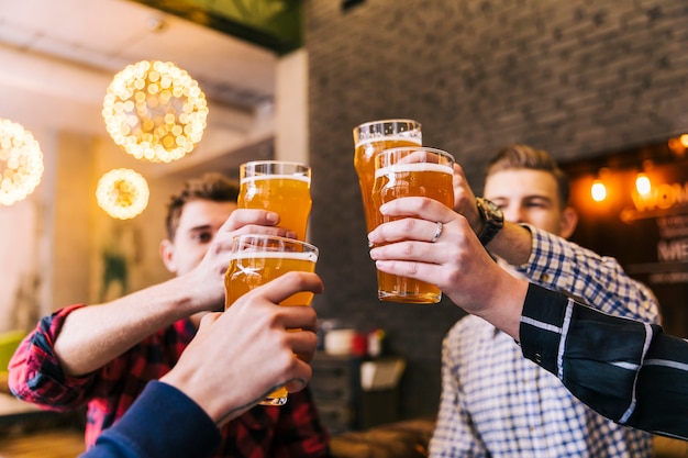 Foto grupo de amigos celebrando el éxito con vasos de cerveza.