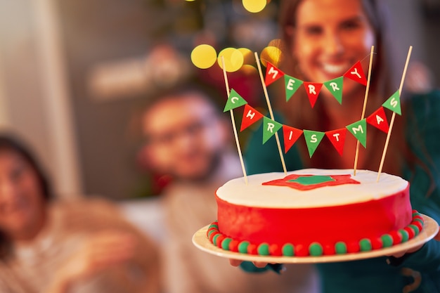 Grupo de amigos celebrando la Navidad en casa disfrutando de la tarta x-mass