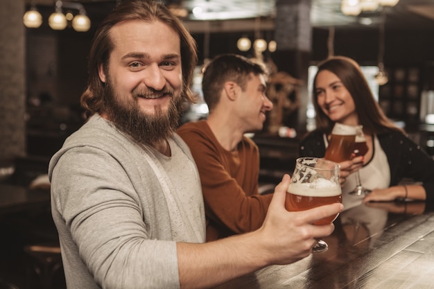 Grupo de amigos celebrando en el pub, bebiendo cerveza juntos