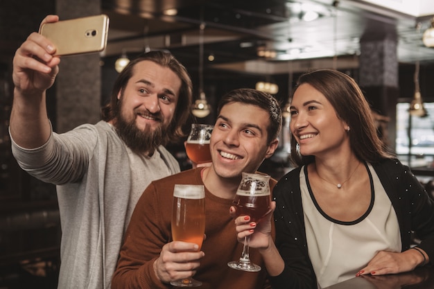 Grupo de amigos celebrando en el pub, bebiendo cerveza juntos