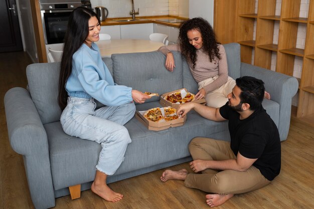 Foto grupo de amigos comiendo pizza juntos en casa