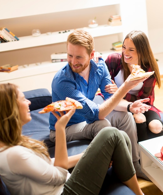 Grupo de amigos comiendo pizza juntos en casa