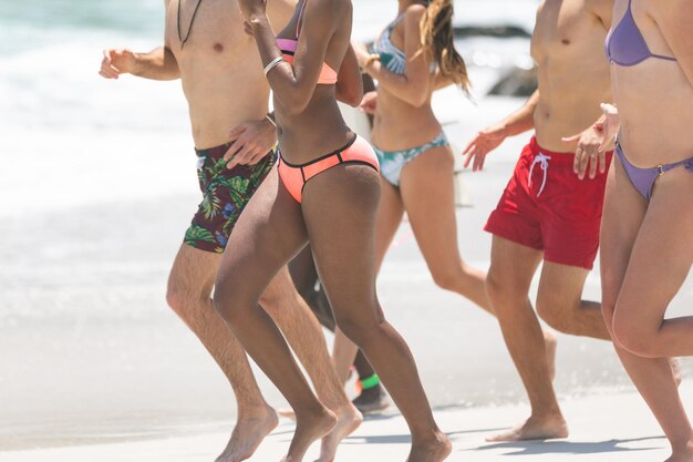 Grupo de amigos corriendo y disfrutando en la playa en un día soleado