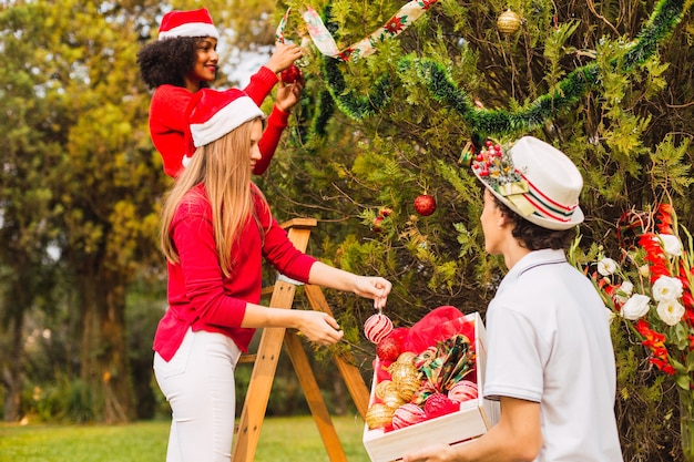 Grupo de amigos decorando un árbol de Navidad