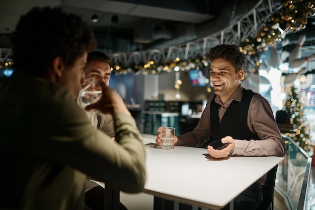 Grupo de amigos descansan en el bar deportivo sentados en la mesa bebiendo y hablando, pasando tiempo en el concepto de club nocturno