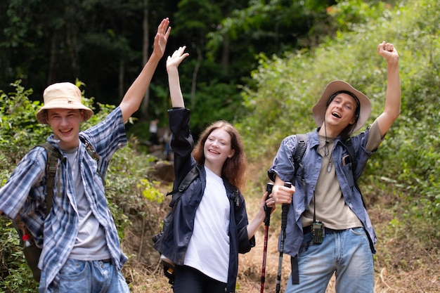 Grupo de amigos en un día soleado en el bosque Joven excursionista de grupo con mochila y palos de trekking