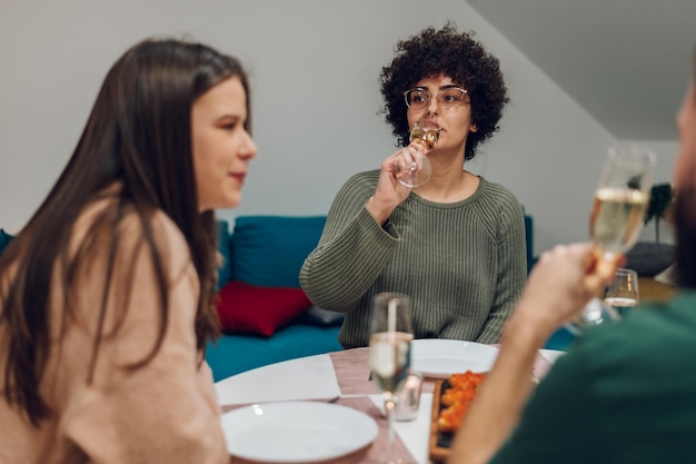 Grupo de amigos disfrutando de la cena sentados juntos en la mesa de la cocina