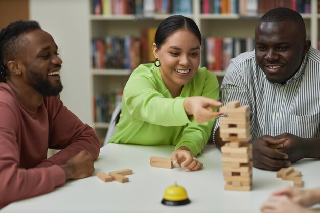 Grupo de amigos disfrutando del juego de la torre de equilibrio en la biblioteca