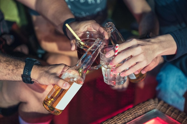 Grupo de amigos disfrutando con tintineo de una cerveza y un cóctel