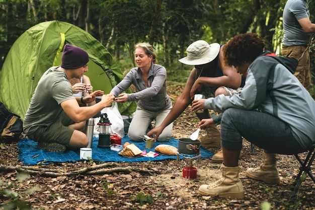 Grupo de amigos diversos acampando en el bosque.