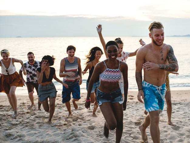 Grupo de amigos diversos corriendo en la playa juntos