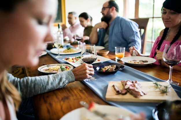 Grupo de amigos diversos están cenando juntos