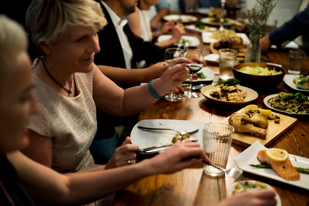 Grupo de amigos diversos están cenando juntos