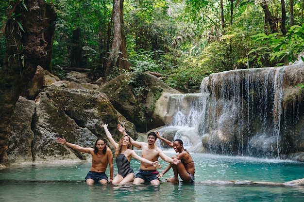 Grupo de amigos diversos que disfrutan de la cascada