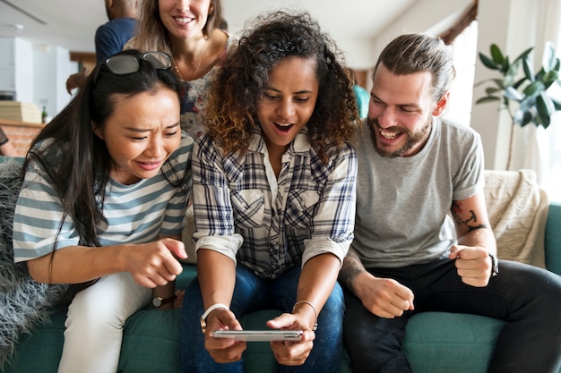 Grupo de amigos diversos que juegan al juego en el teléfono móvil