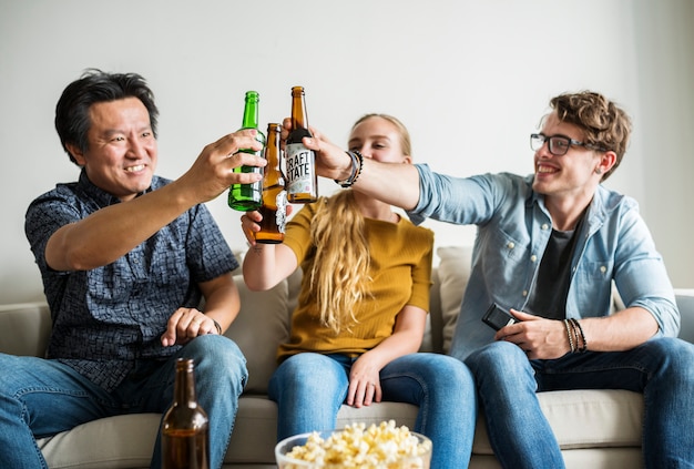 Grupo de amigos diversos que tienen una noche de cine bebiendo cerveza.