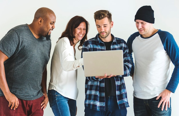 Grupo de amigos diversos que usan la computadora portátil junto