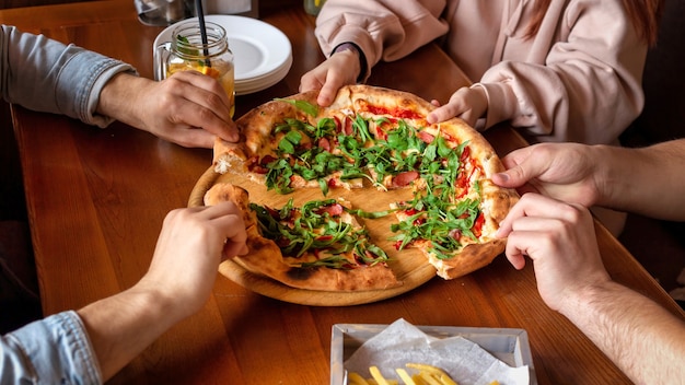 Un grupo de amigos dividiendo pizza en un pub. Amistad