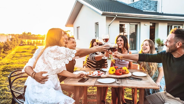 Grupo de amigos divirtiéndose en una barbacoa al aire libre cenando en el jardín de su casa