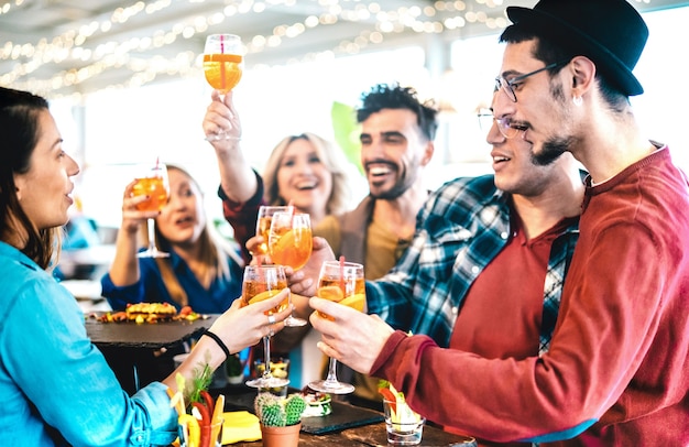 Grupo de amigos divirtiéndose en el buffet de aperitivos de la fiesta previa a la cena bebiendo cócteles y comiendo bocadillos