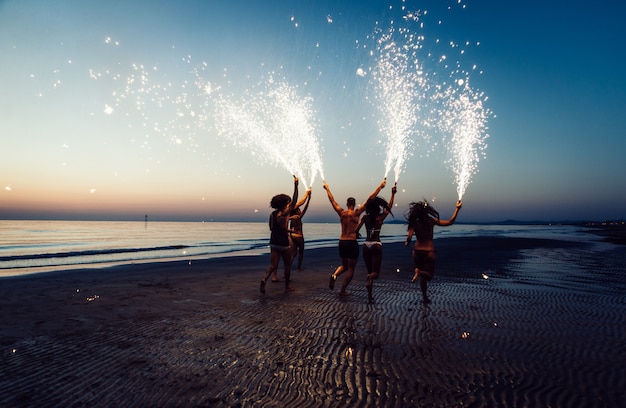 Grupo de amigos divirtiéndose corriendo en la playa con estrellitas