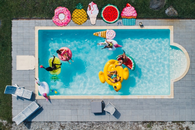 Foto grupo de amigos divirtiéndose en la piscina con diferentes camas de aire