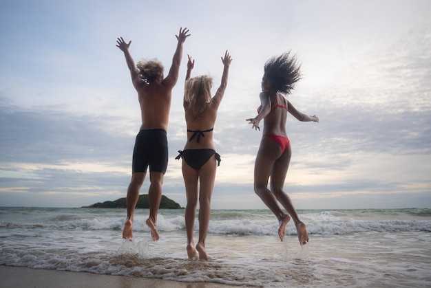 Grupo de amigos divirtiéndose en la playa al atardecer