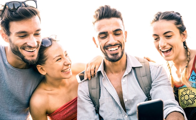 Grupo de amigos divirtiéndose usando teléfonos móviles inteligentes