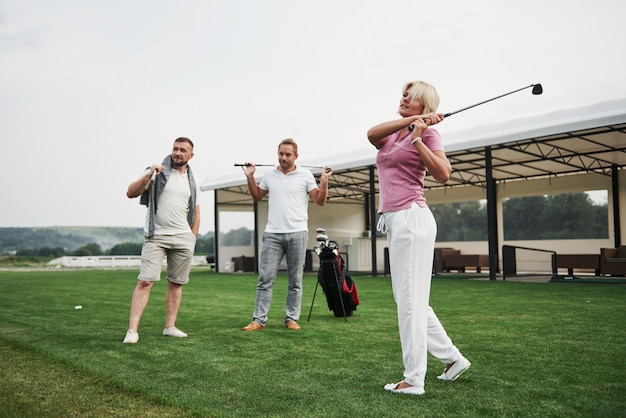 Grupo de amigos elegantes en el campo de golf aprenden a jugar un nuevo juego