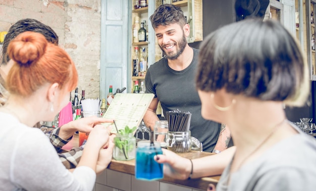 Foto un grupo de amigos eligiendo un cóctel del menú en un bar