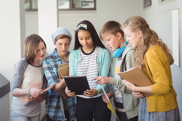 Grupo de amigos de la escuela mediante tableta digital en el pasillo