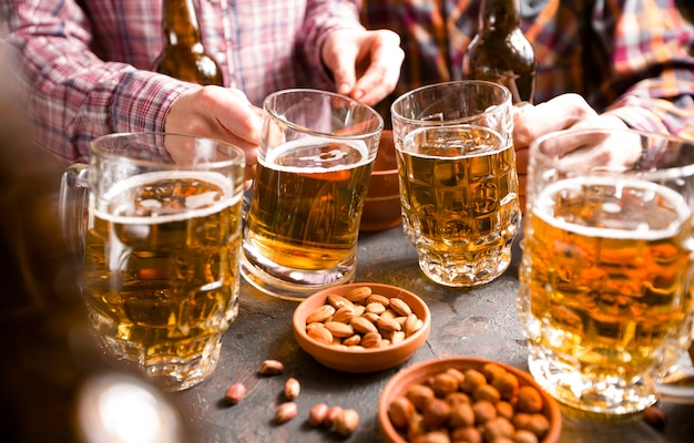 Un grupo de amigos está bebiendo cerveza de tazas en un bar en la mesa.