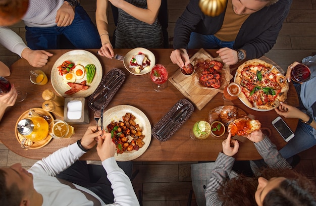 Foto grupo de amigos europeos disfrutando de comida para una mesa grande