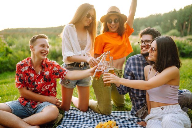 Foto grupo de amigos felices animados bebiendo cervezas en el parque de verano concepto de amistad o fiesta