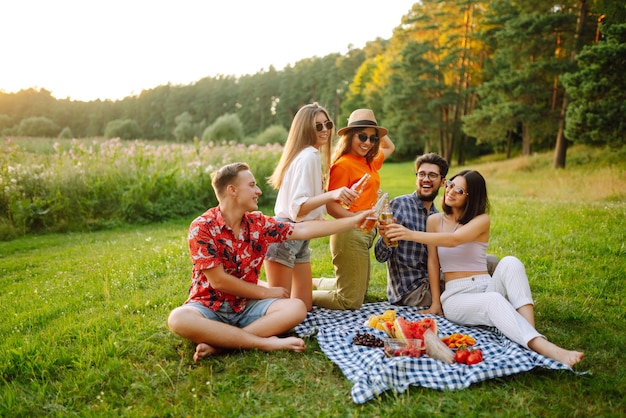Grupo de amigos felices animados bebiendo cervezas en el parque de verano concepto de amistad o fiesta