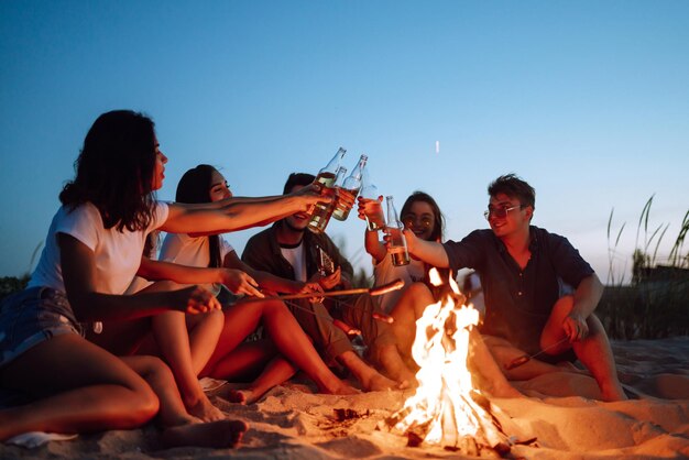 Grupo de amigos felices animando y bebiendo cervezas en la playa disfrutando de las vacaciones Tiempo de vacaciones riendo