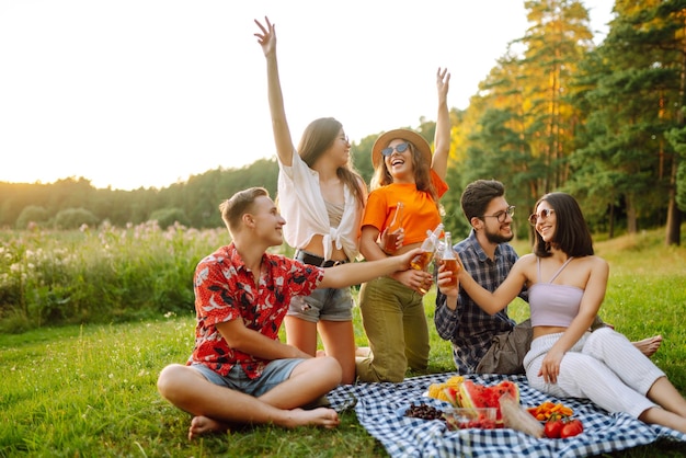 Foto grupo de amigos felices aplausos beben cervezas en el parque de verano amistad o concepto de vacaciones