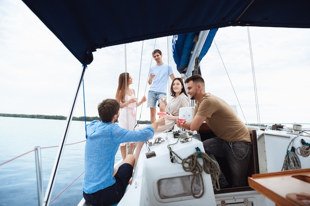 Grupo de amigos felices bebiendo cócteles de vodka en fiesta en barco al aire libre, verano