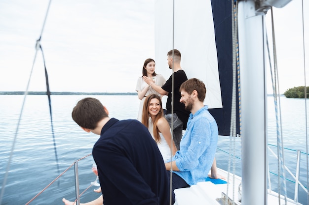 Foto grupo de amigos felices bebiendo cócteles de vodka en fiesta en barco al aire libre, verano